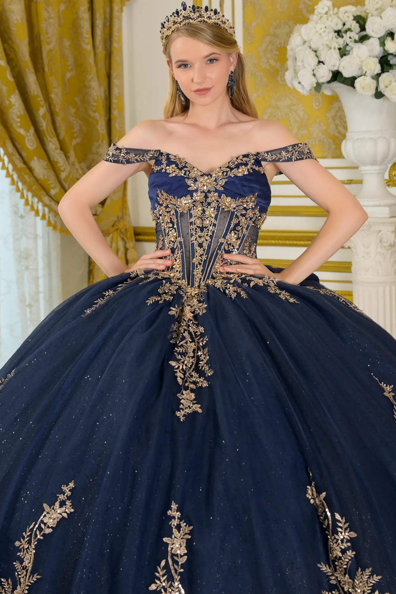 Close-up front view of navy quinceañera ball gown highlighting gold embroidered corset bodice, off-the-shoulder neckline, structured boning, and glitter tulle skirt