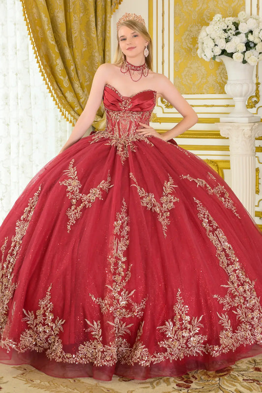 Front view of burgundy quinceañera ball gown with strapless sweetheart neckline, gold embroidered corset bodice, glitter tulle skirt, and dramatic volume in a luxury interior