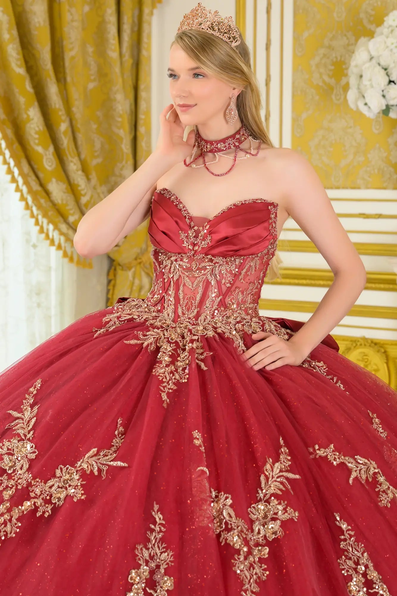 Close-up front view of burgundy quinceañera ball gown highlighting embroidered corset bodice, sweetheart neckline, structured boning, and glitter tulle skirt
