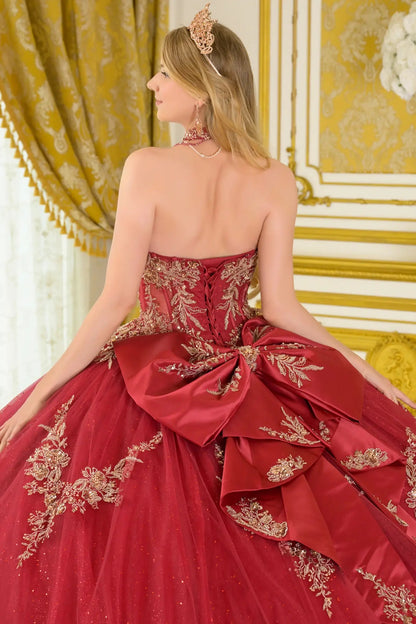 Close-up back view of burgundy quinceañera ball gown with lace-up corset back, gold embroidered detailing, detachable bow, and voluminous tulle skirt