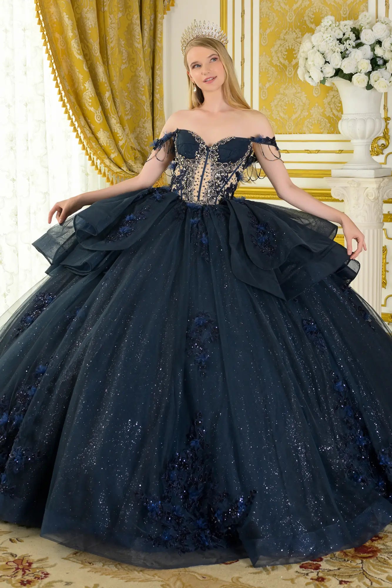 Front view of navy quinceañera ball gown with off-the-shoulder sweetheart neckline, crystal-embellished corset bodice, layered glitter tulle skirt, and dramatic volume in a luxury interior