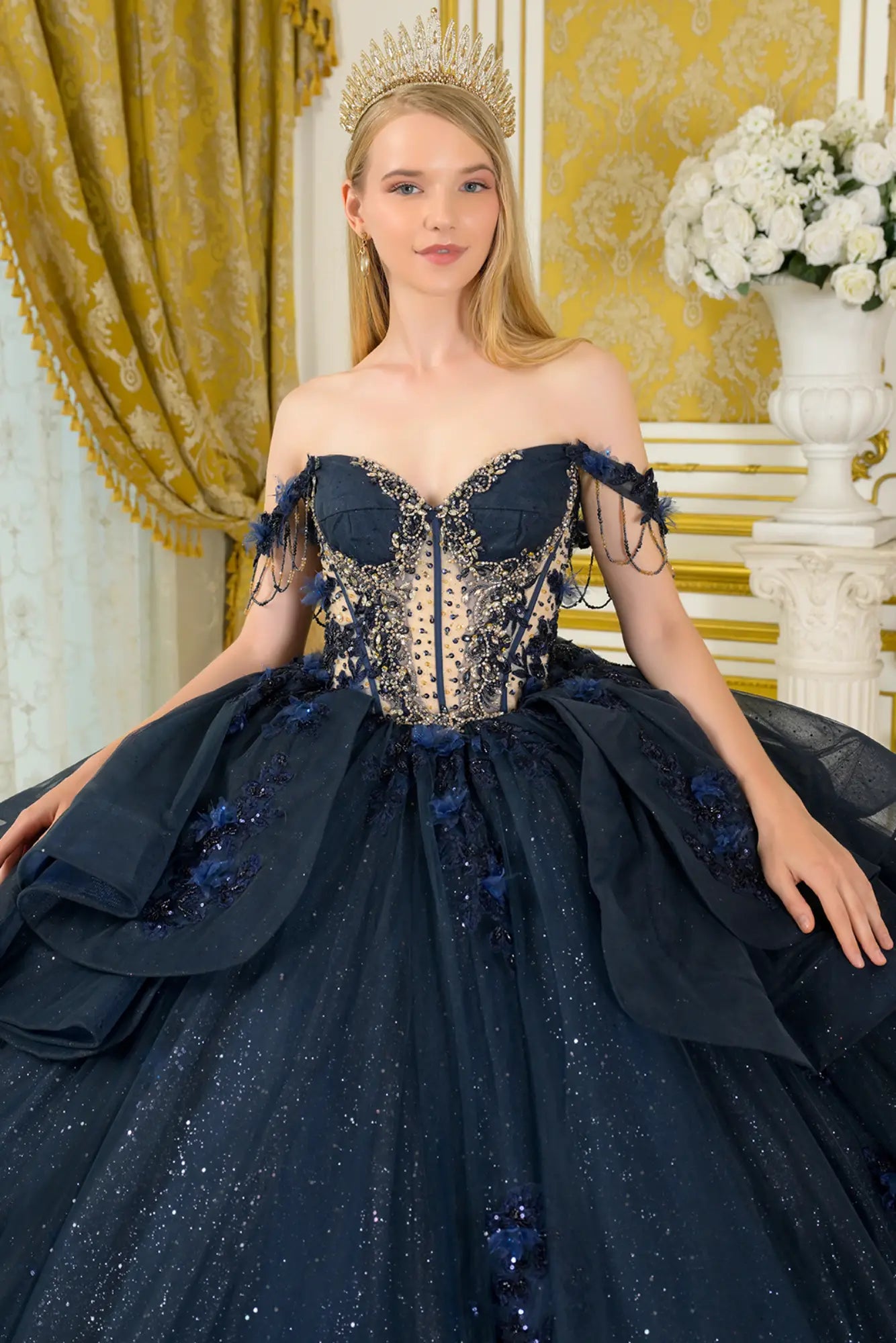 Close-up front view of navy quinceañera ball gown showing crystal-embellished corset bodice, sweetheart neckline, sheer paneling, and off-the-shoulder beaded straps