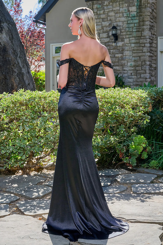Back full-length view of a black fitted prom dress with off-shoulder straps, sheer embroidered corset bodice, satin skirt, gathered back, and a thigh-high slit.