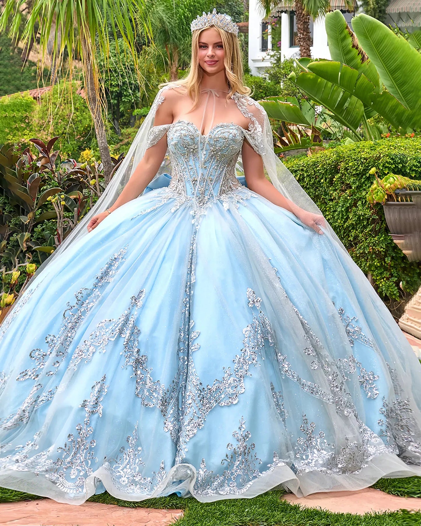 Woman in a light blue ball gown with silver embellishments in a garden setting
