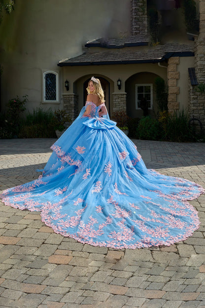 Blue and pink ball gown on a cobblestone path in front of a house.