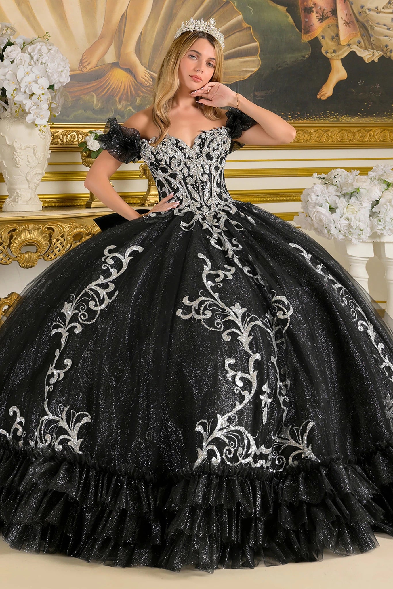 Woman in a black and silver ball quince gown standing in an ornate room with decorative elements.