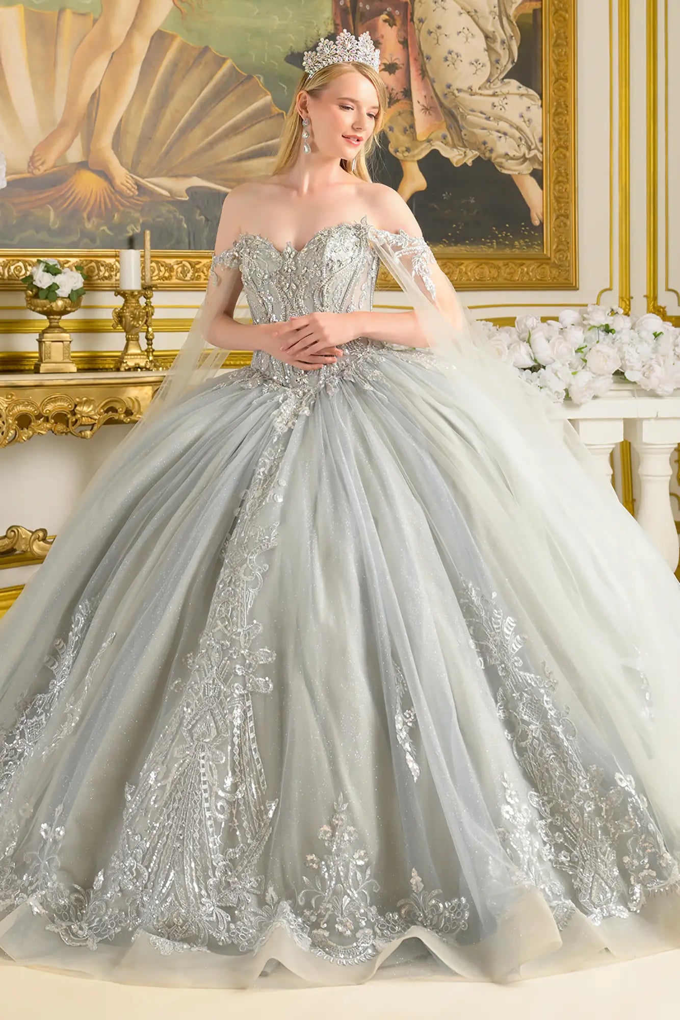 Girl wearing a silver quinceañera dress with intricate detailing in an elegant room.