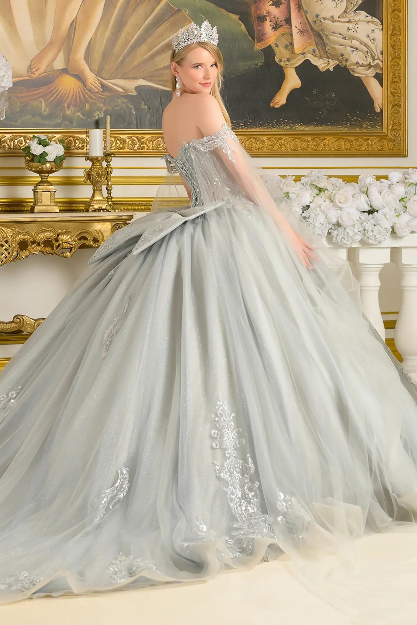Girl wearing a silver quinceañera dress with intricate detailing in an elegant room.