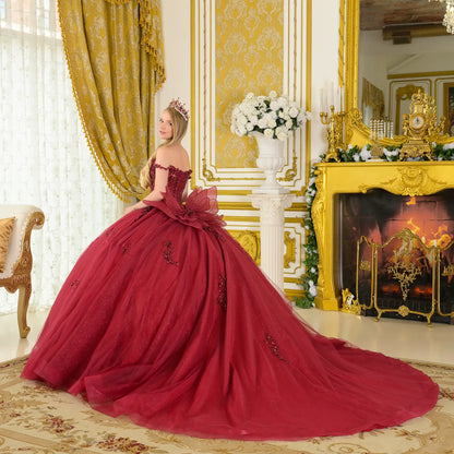 Girl wearing a burgundy quinceañera dress with tiara in an opulent room with gold decor and a fireplace.