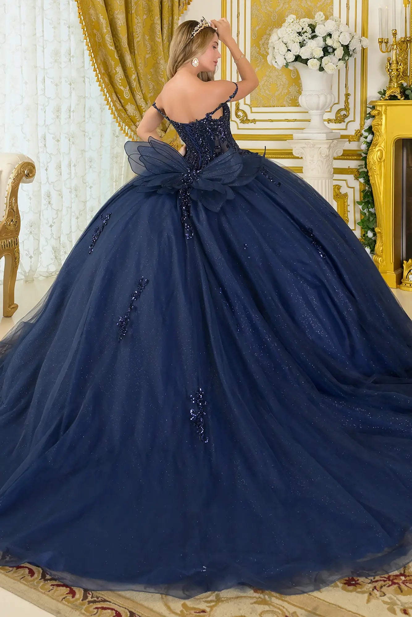 Girl in a quinceañera dress with satin-decorated bodice with a tiara in an elegant interior setting.