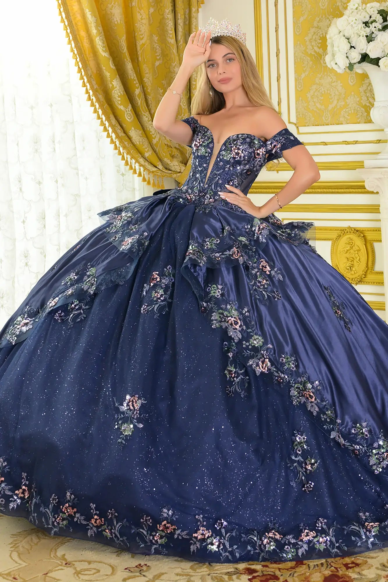 Girl wearing a navy quinceañera dress with satin-decorated bodice in a decorated room.