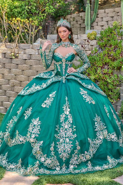 Woman in a green with silver ball gown with intricate silver embroidery standing outdoors.