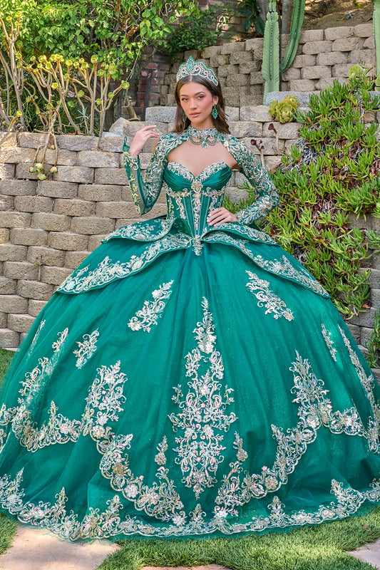 Woman in a green with silver ball gown with intricate silver embroidery standing outdoors.