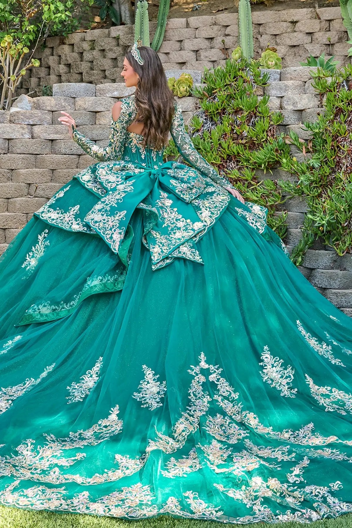 green quince ball gown with white lace details against a stone wall and cactus background