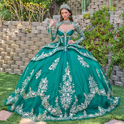 Woman in a green ball gown with silver embroidery standing outdoors against a stone wall.