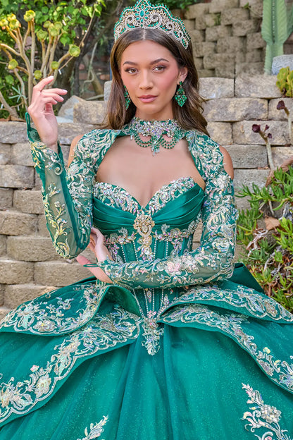 Woman in a green embroidered dress with a tiara outdoors.