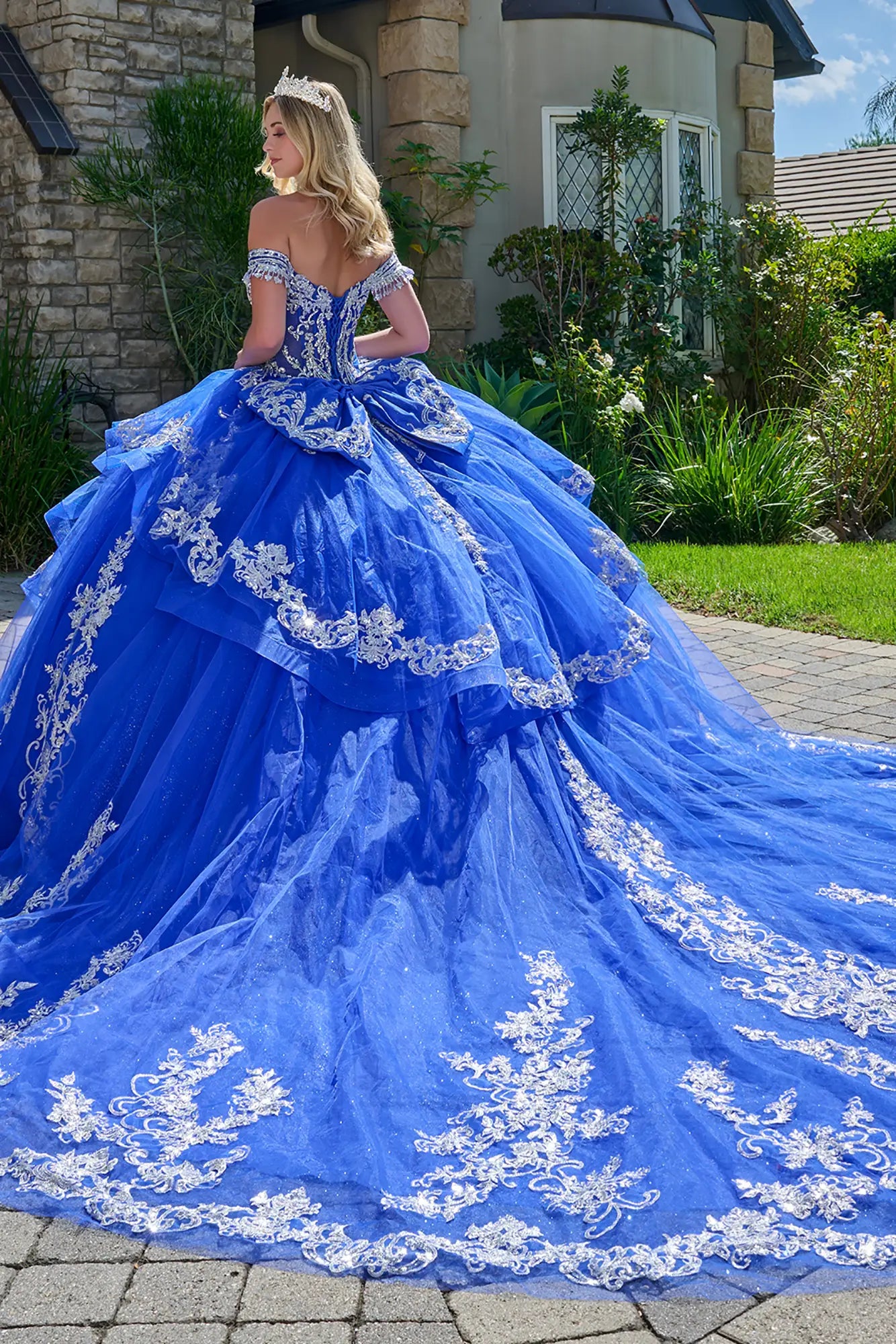 Girl wearing a royal blue quinceañera dress with a tiara, standing outdoors.