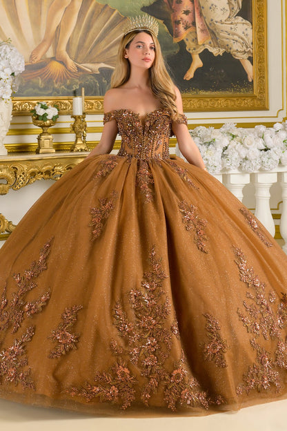 Woman in an ornate brown quince dress with floral embellishments in a decorated room.