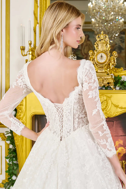 Woman wearing a wedding gown with corset closure, sheer sleeves, and flowing train