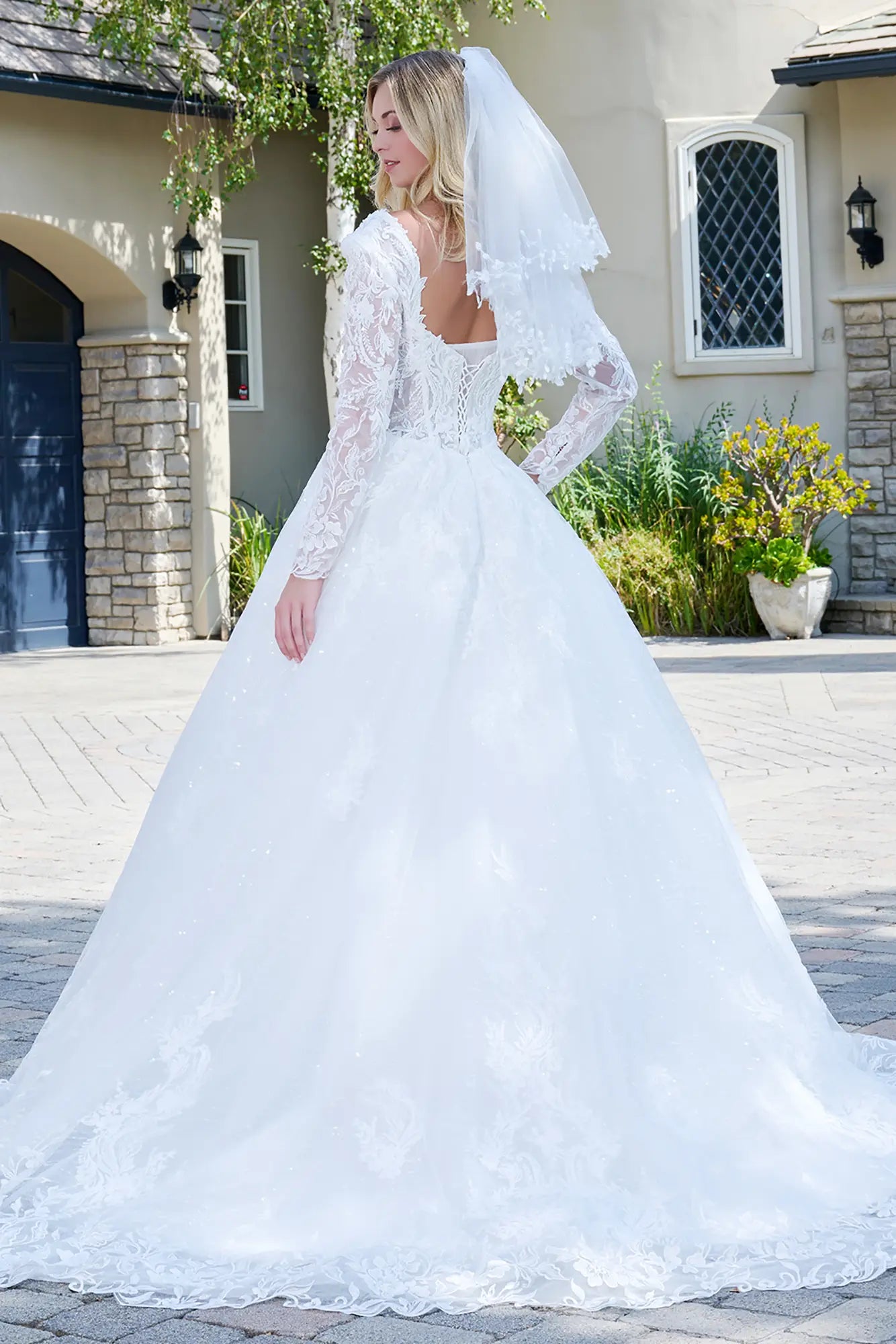 Woman in a white wedding dress standing outside a house.