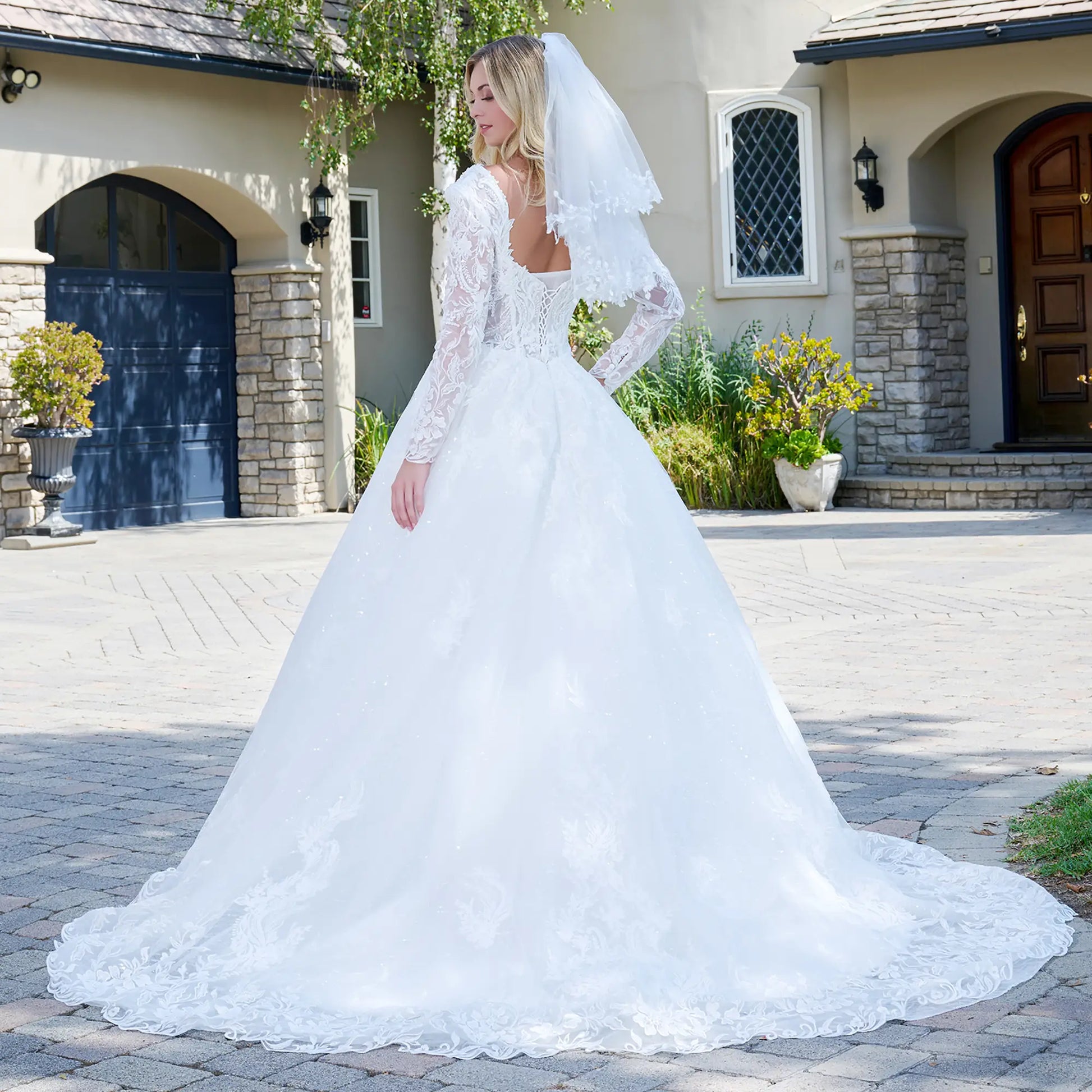 Woman in a white wedding dress standing in front of a house.