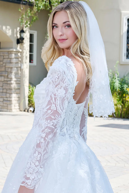 Woman wearing a white lace wedding dress with a veil outdoors.