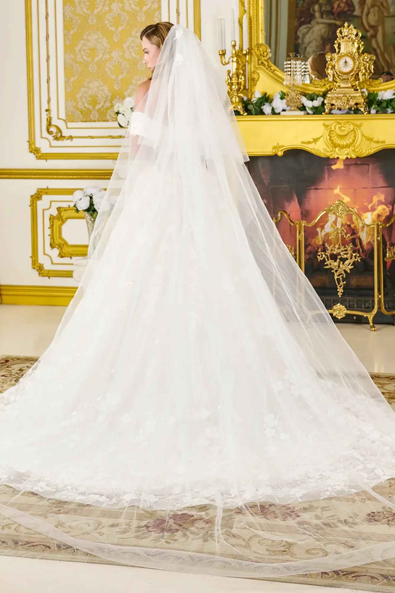 Bride in a white wedding dress with a long veil in an ornate room.