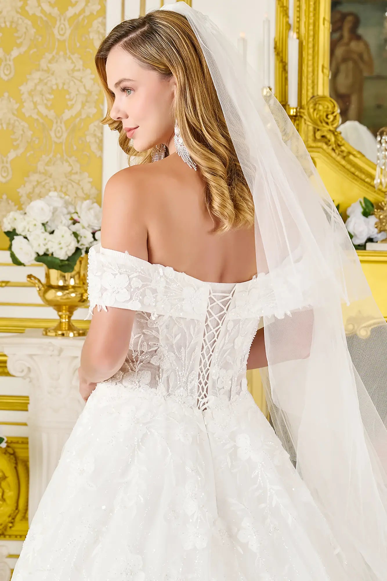 Woman in a white wedding dress with a long veil in a decorated room.