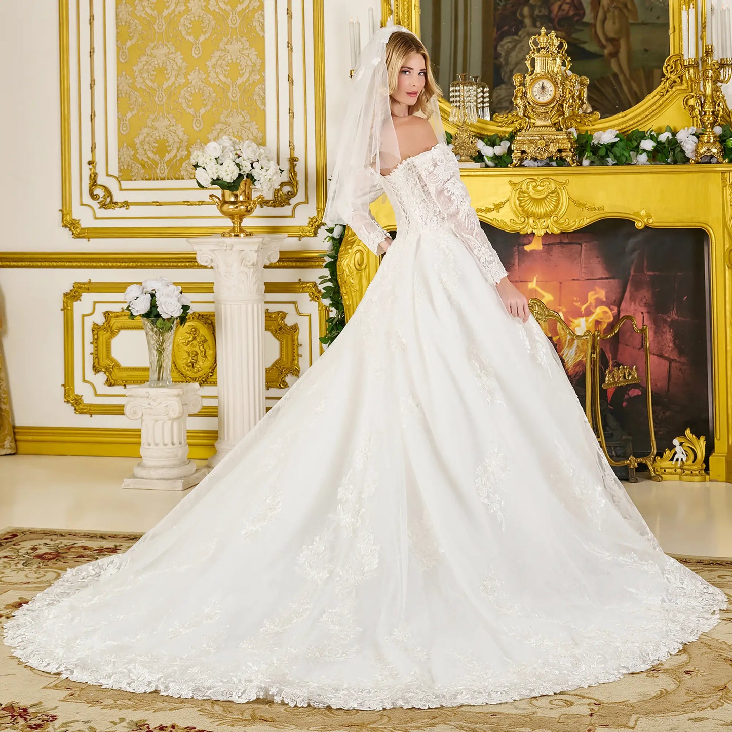 Woman in a white wedding dress standing in an opulent room with gold decor.