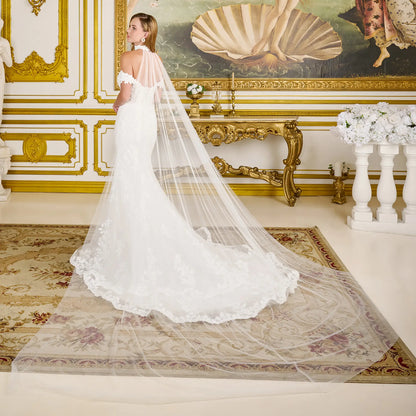 Woman in a white wedding dress with a long veil in an ornate room.