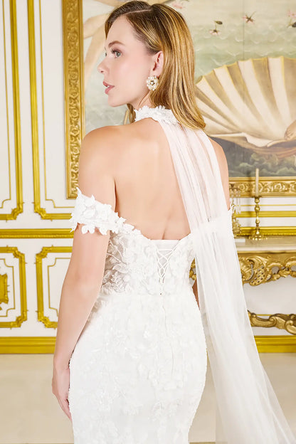 Woman in a white wedding dress with floral details in an elegant interior setting.