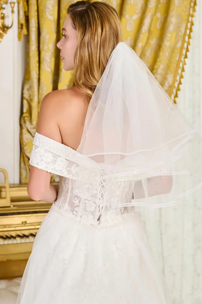 Woman wearing a white wedding dress with a veil in a decorated room.