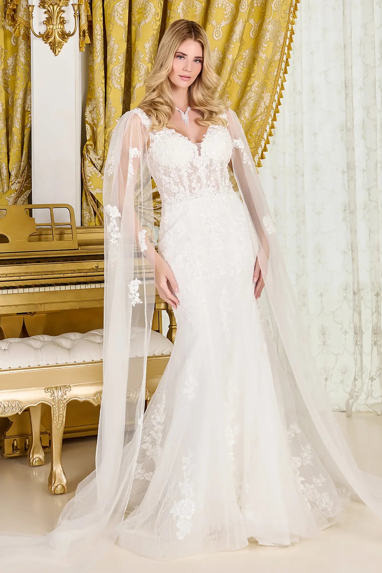Woman in a white wedding dress standing in a room with gold curtains and a piano.