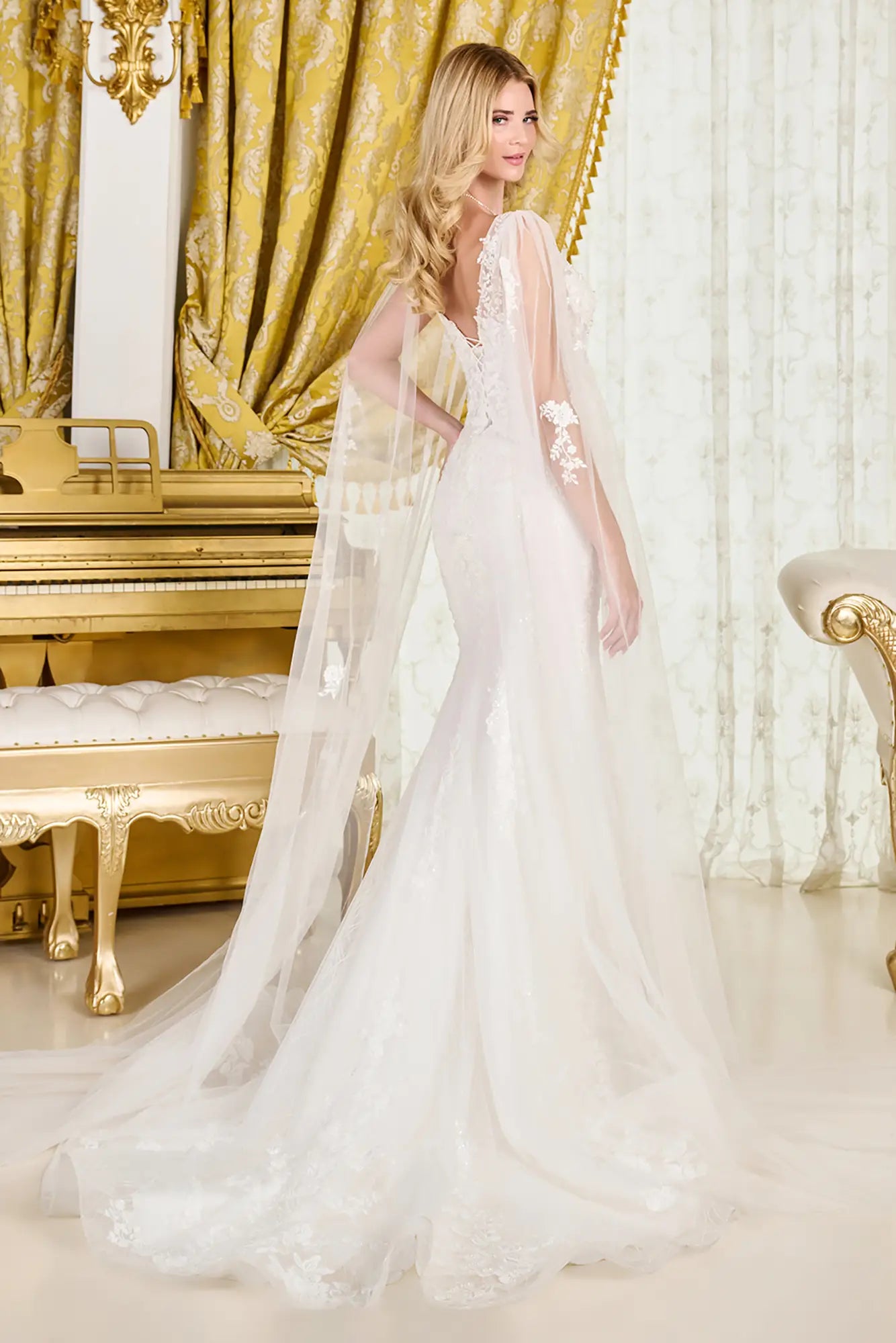 Woman in a white wedding dress standing in an opulent room with gold accents.