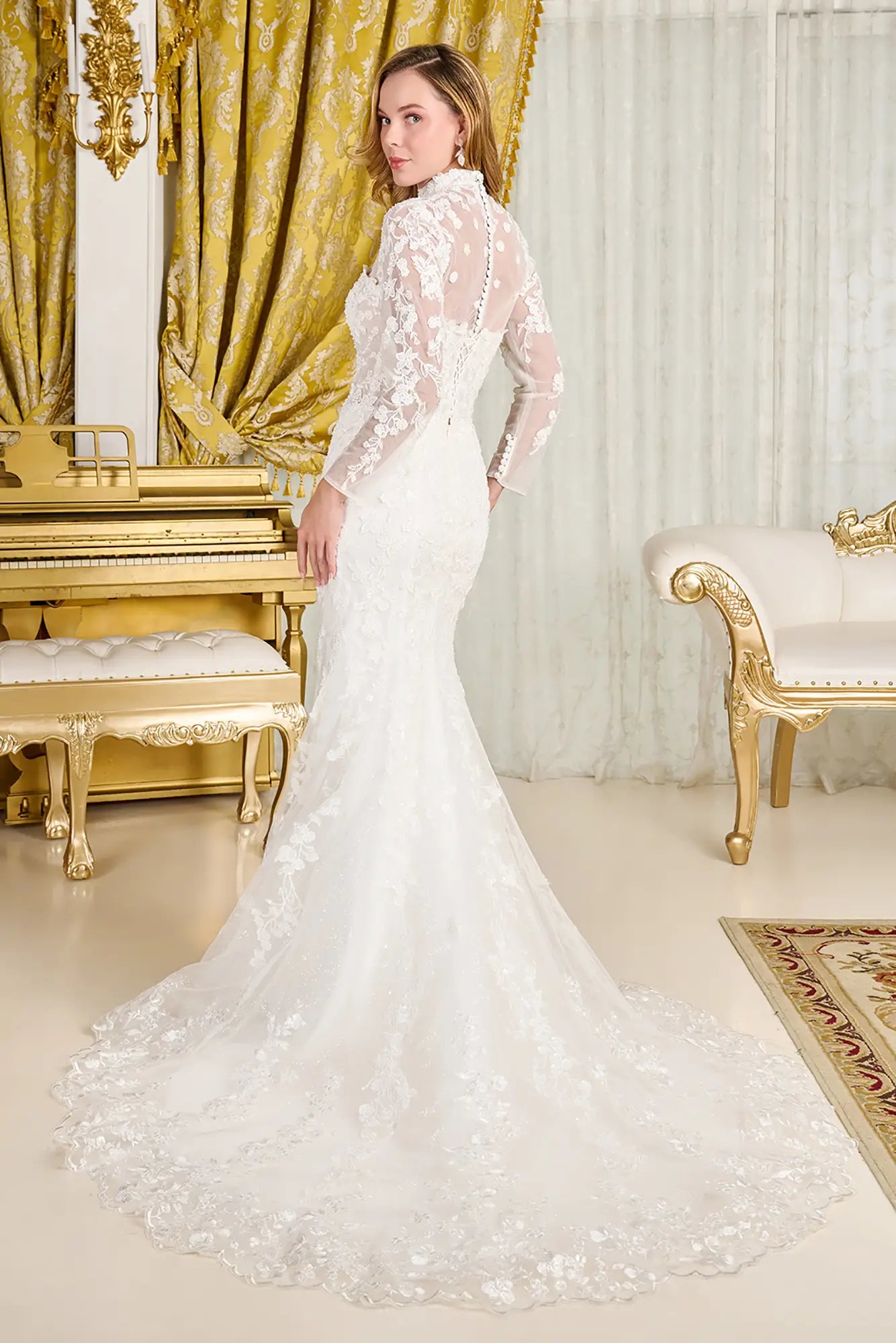 Woman in a white wedding dress standing in an opulent room with gold accents.