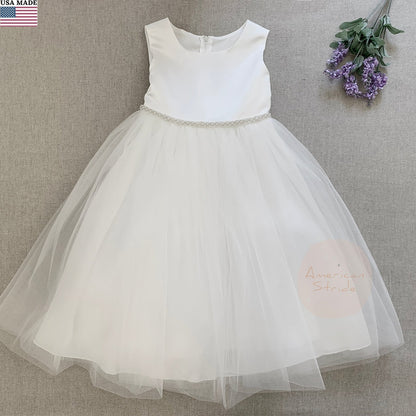 White flower girl dress with a sheer skirt on a gray background