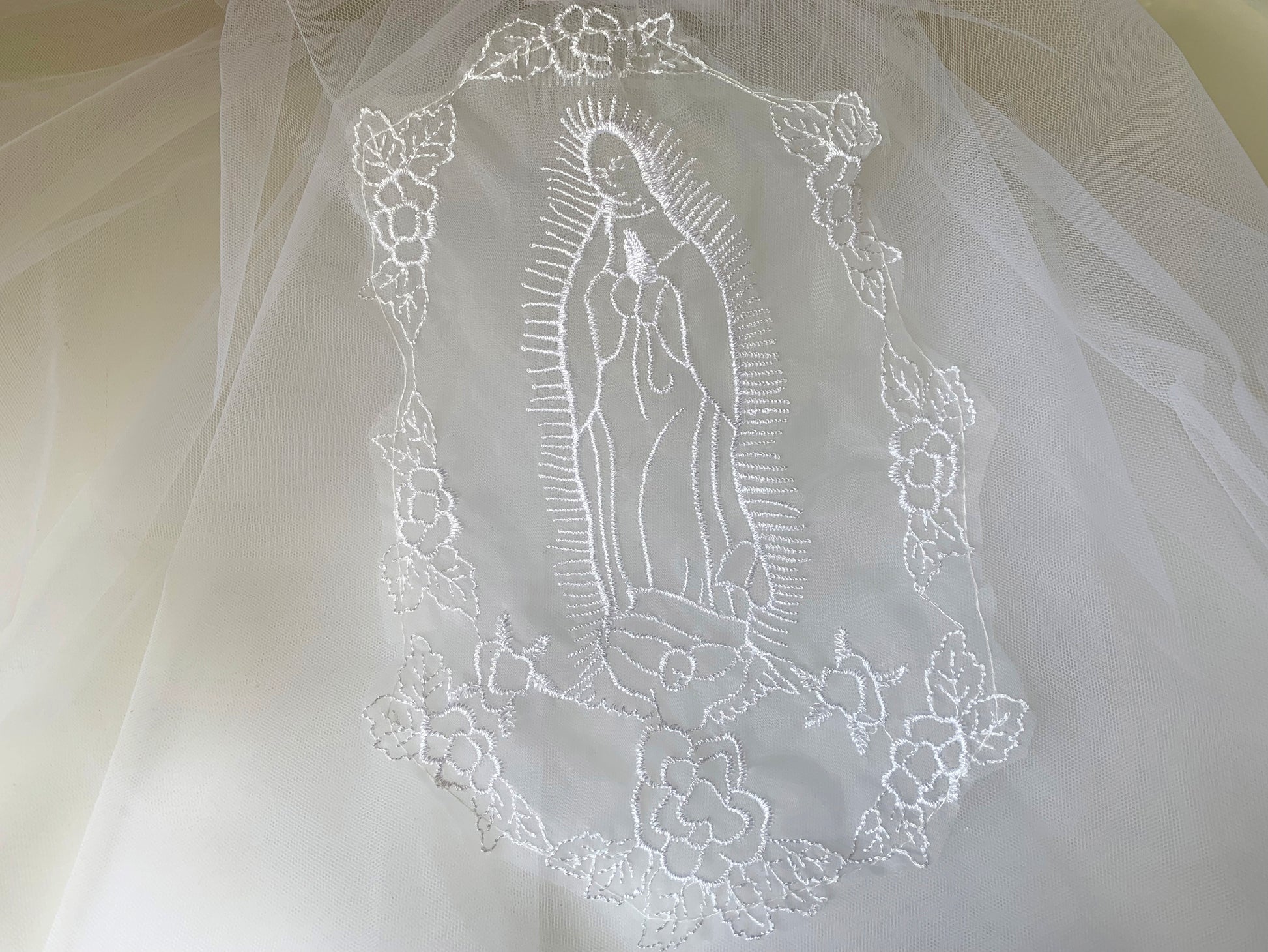 Embroidered design of a religious figure on a white fabric background