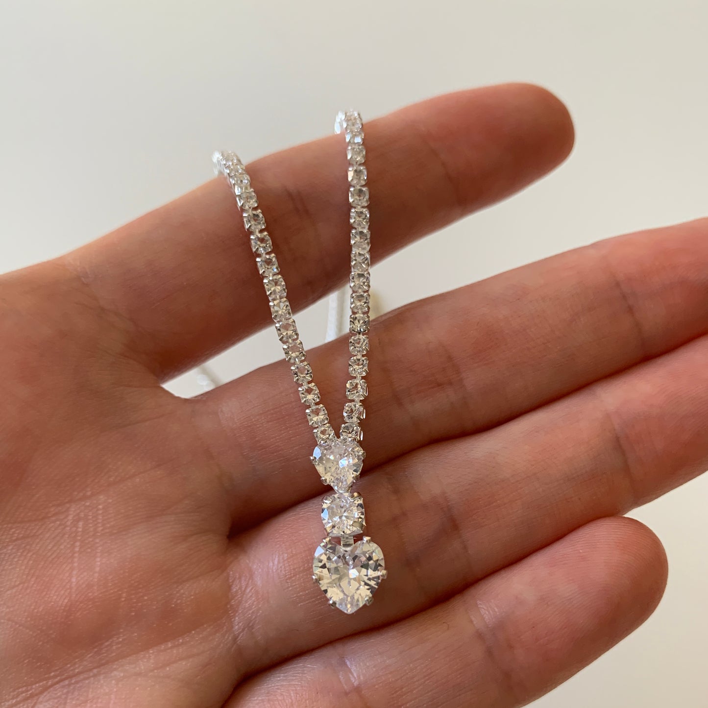 full rhinestone necklace held by a hand against a neutral background