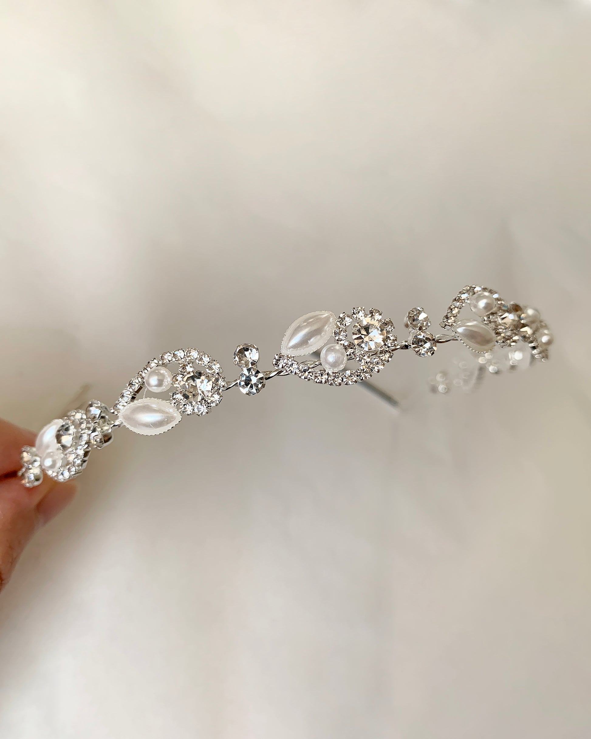 Silver headband with pearls and crystals on a plain background