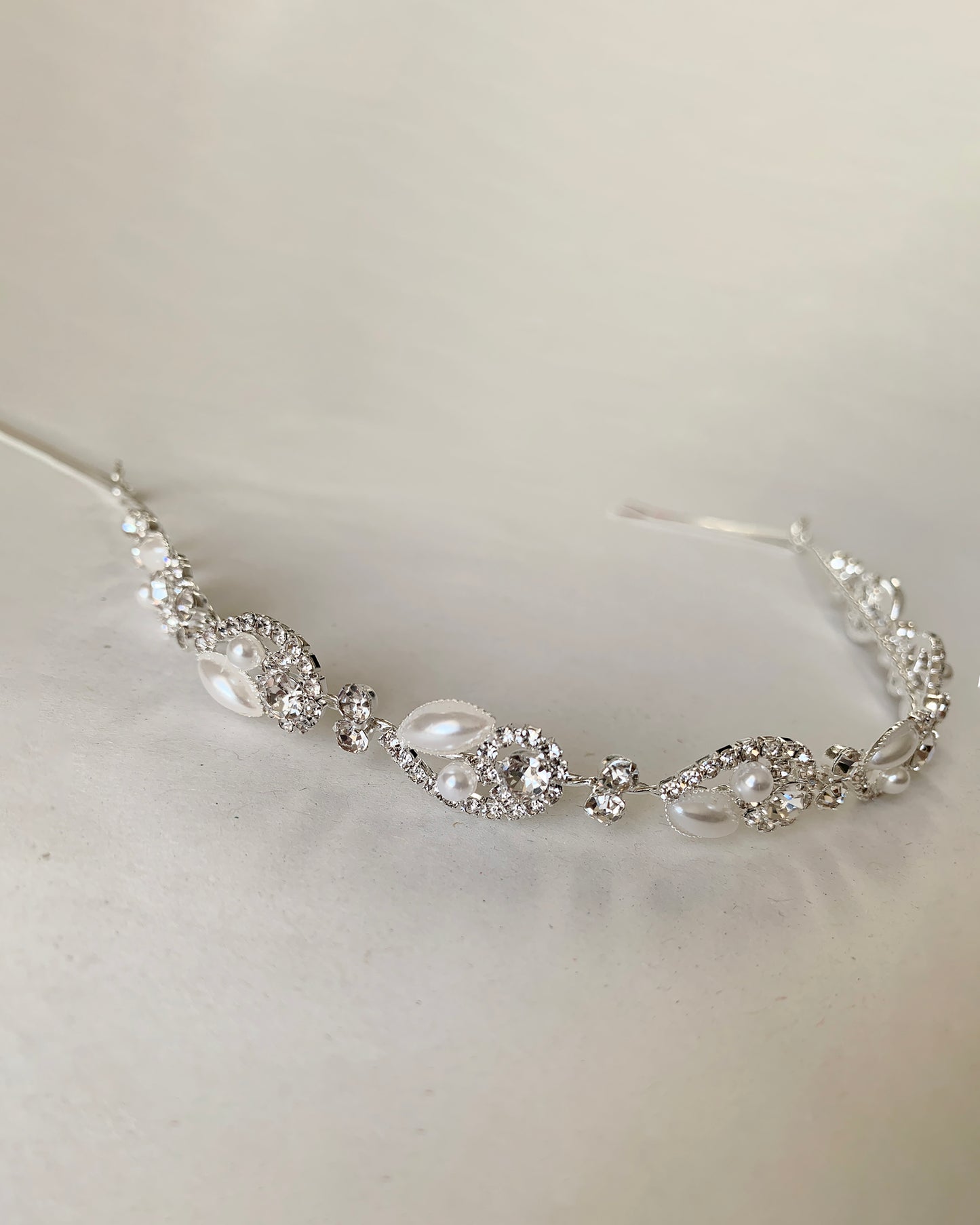 Silver headpiece with pearl and crystals on a light gray background