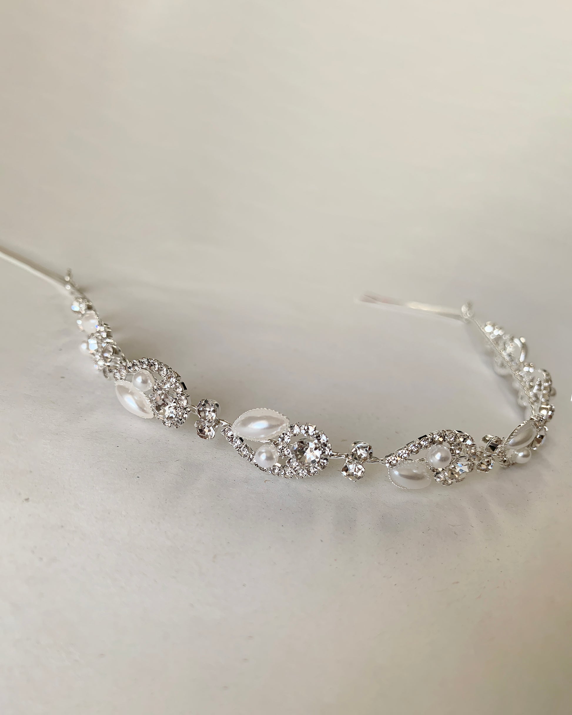 Silver headpiece with pearl and crystals on a light gray background
