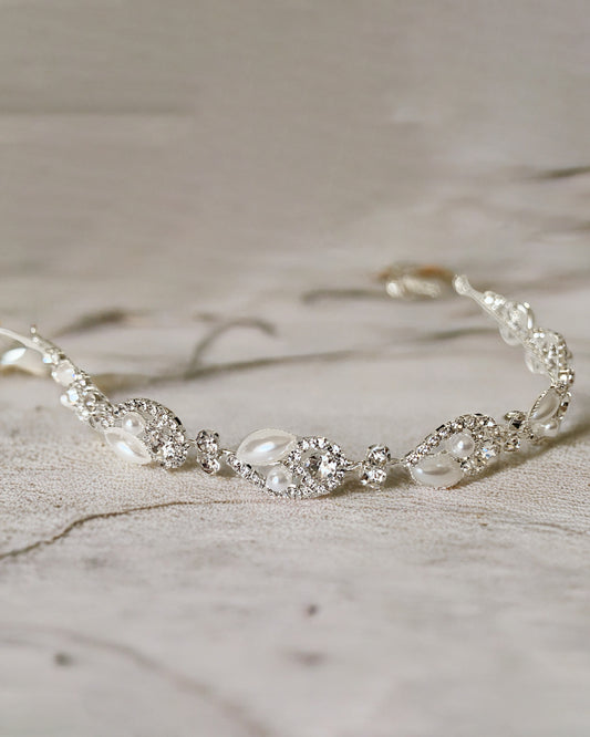 Silver bridal headpiece with pearls and crystals on a textured surface