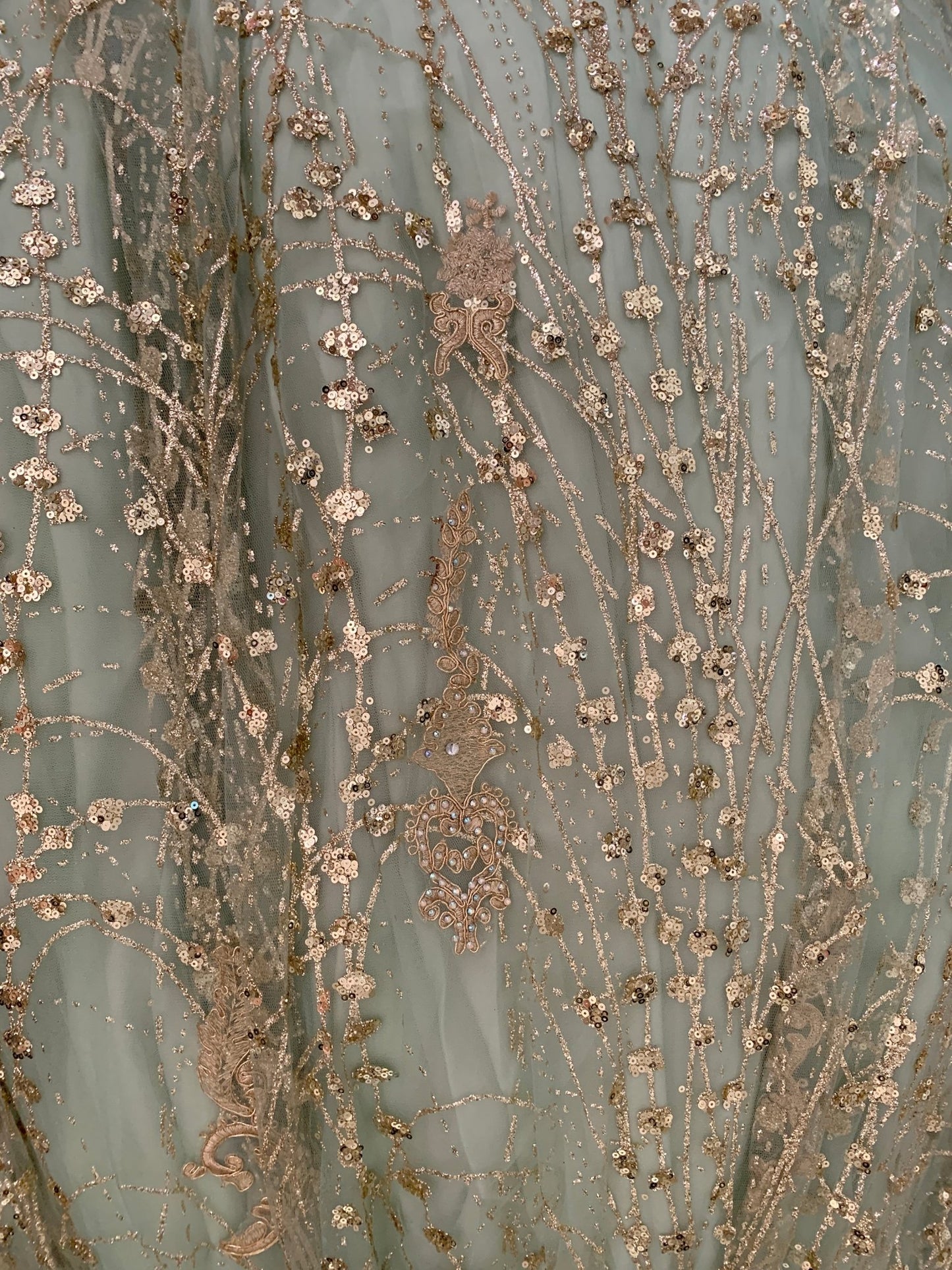 Close-up of a textured fabric with floral patterns and metallic accents on a light blue background.