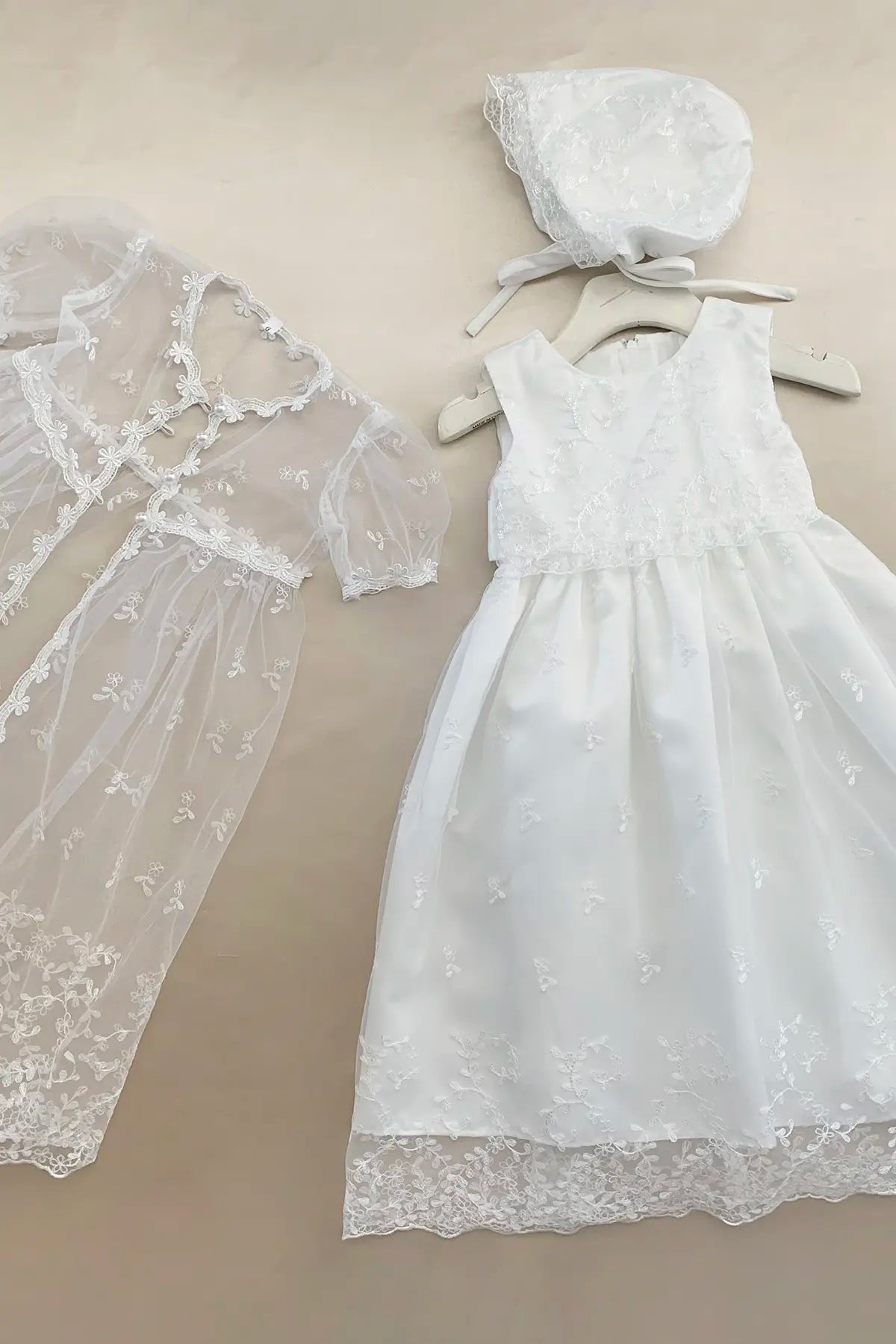 White lace dress and bonnet on a beige background