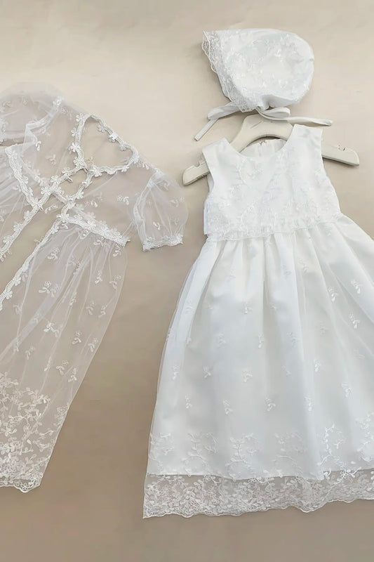 White lace dress and bonnet on a beige background