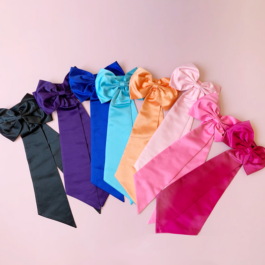 Set of colorful satin hair bows on a pink background