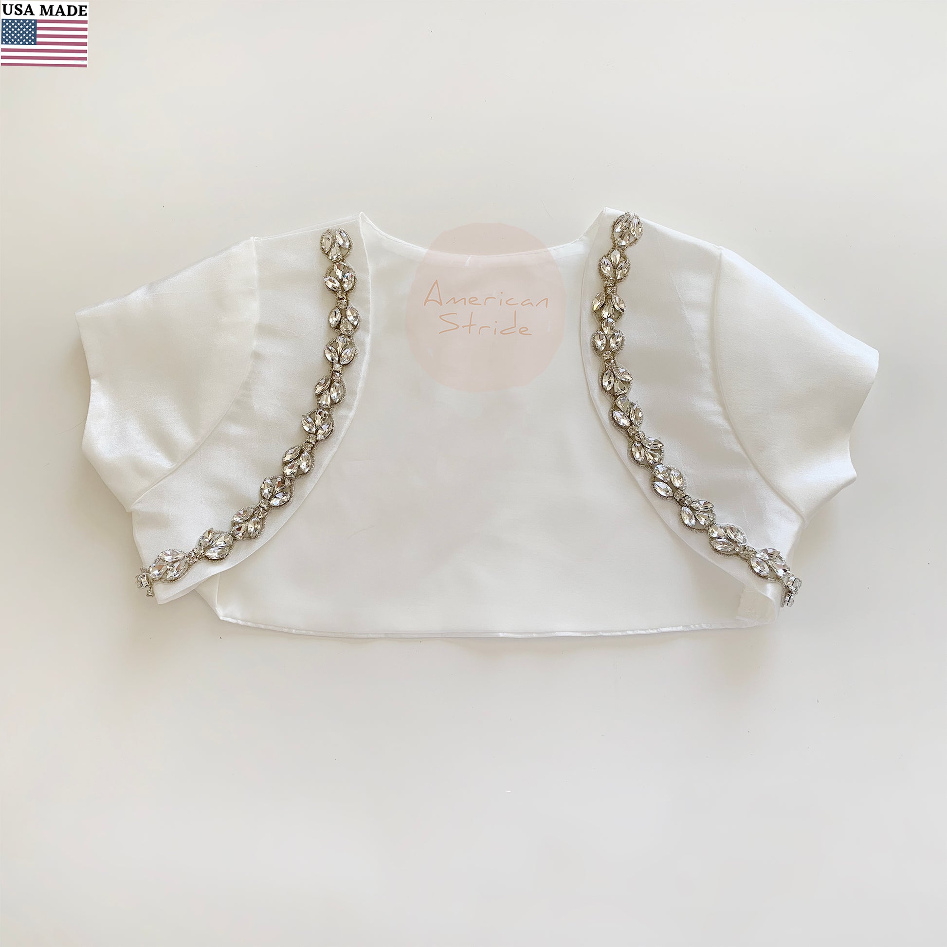 White bolero jacket with decorative rhinestone trim on a light background