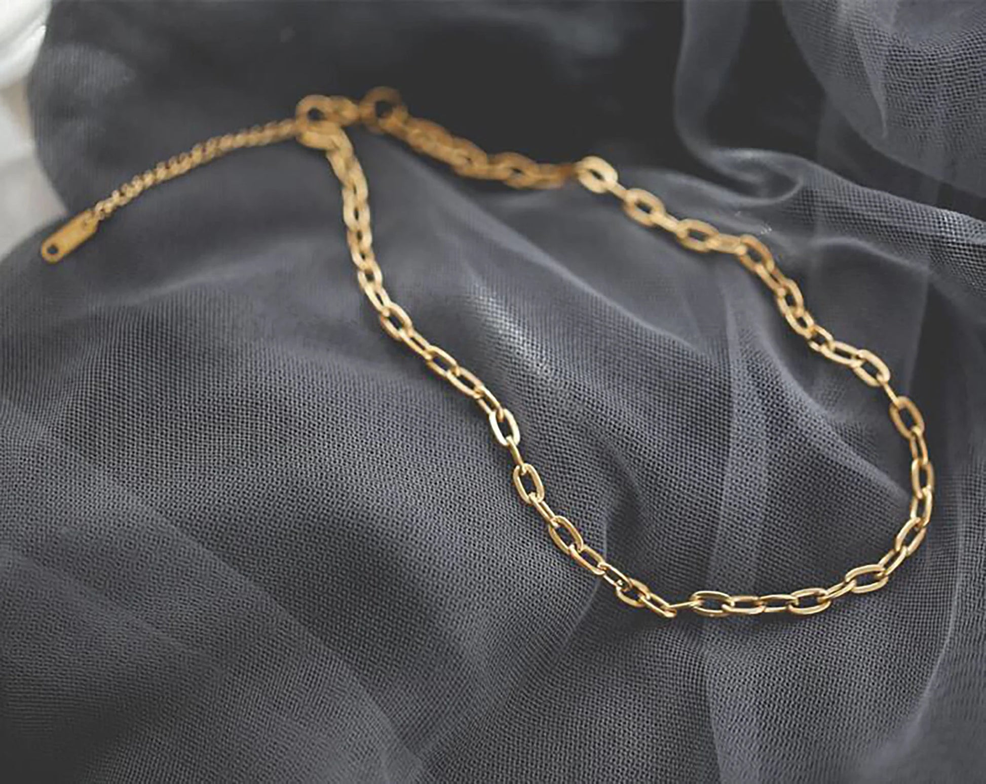 Gold chain necklace on a dark fabric background