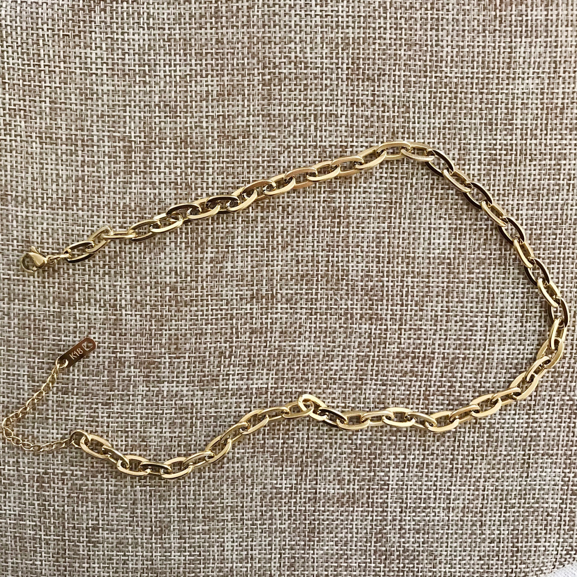 Gold chain necklace on a textured beige fabric background
