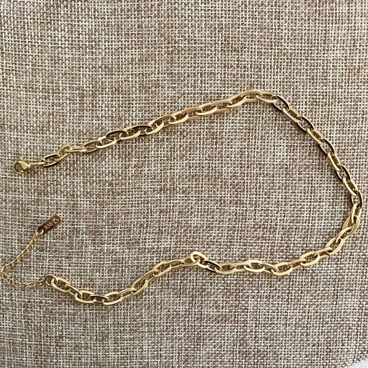 Gold chain necklace on a textured beige fabric background